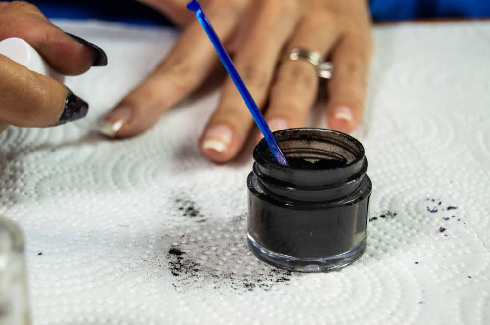 Black acrylic dip powder sitting on white paper towel