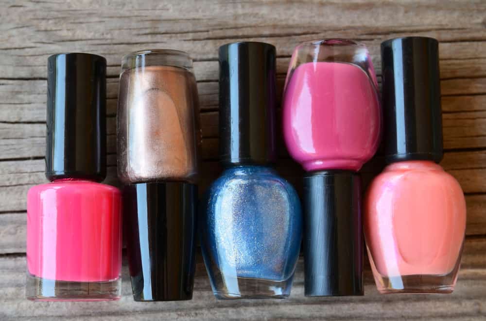 Colorful, bright and glittery nail polish bottles on a wooden background