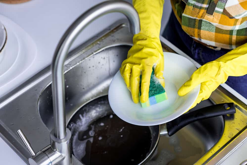 Cropped image of woman washing plate with washing sponge