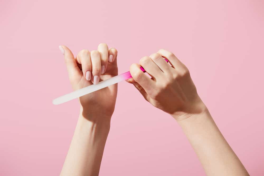 Cropped view of woman filing fingernail with nail file