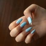 Damaged nail polish of blue color on regrowth nails of the hand