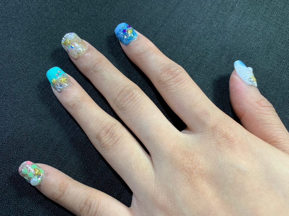 Female hand with turquoise nail design and sea stones