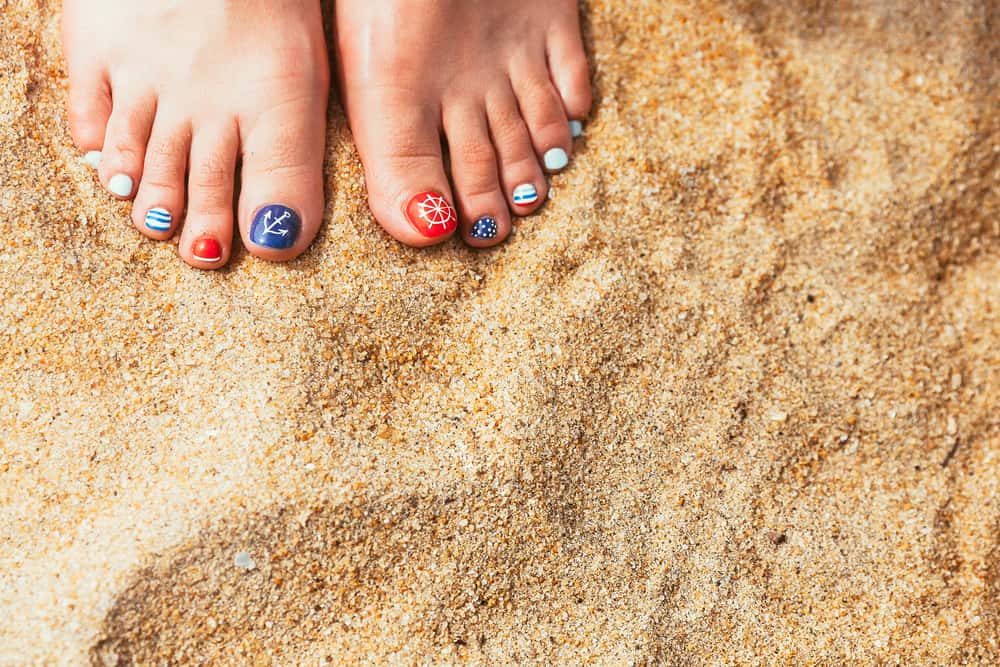 Female sea style pedicured feet on summer shore