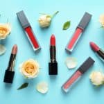 Flat lay composition with lipsticks and roses on color background