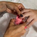 Manicurist using dip powder to give a girl a manicure