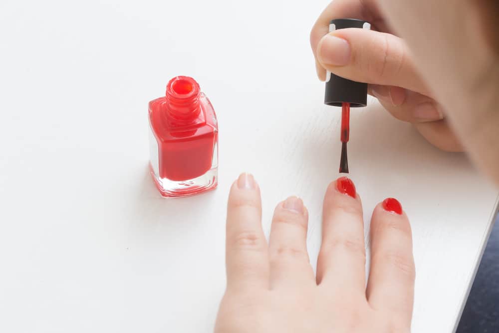 Putting a red varnish on nails on a hand