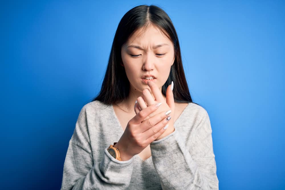 woman wearing casual sweater standing over blue isolated background Suffering pain on hands