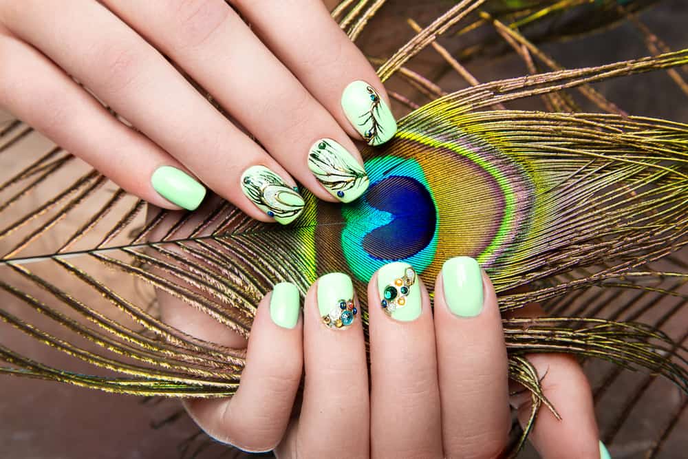 Art design manicure with peacock feather on female hands