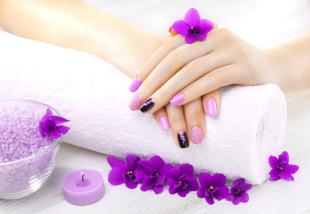 Beautiful purple manicure with violet, candle and towel