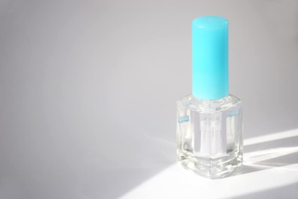 Bottle of clear nail polish for manicure on a light background