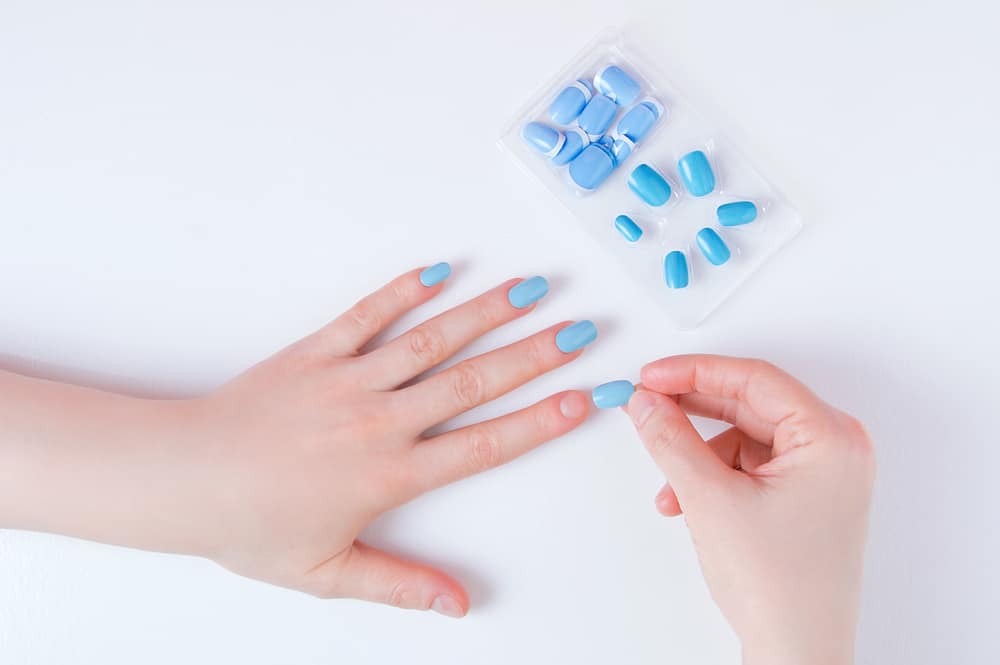 Manicure on a woman hand with false nails on a white background