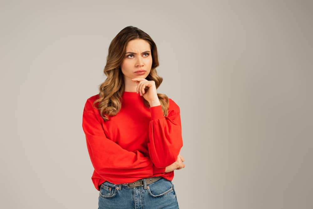 Woman in red sweatshirt looking away and thinking