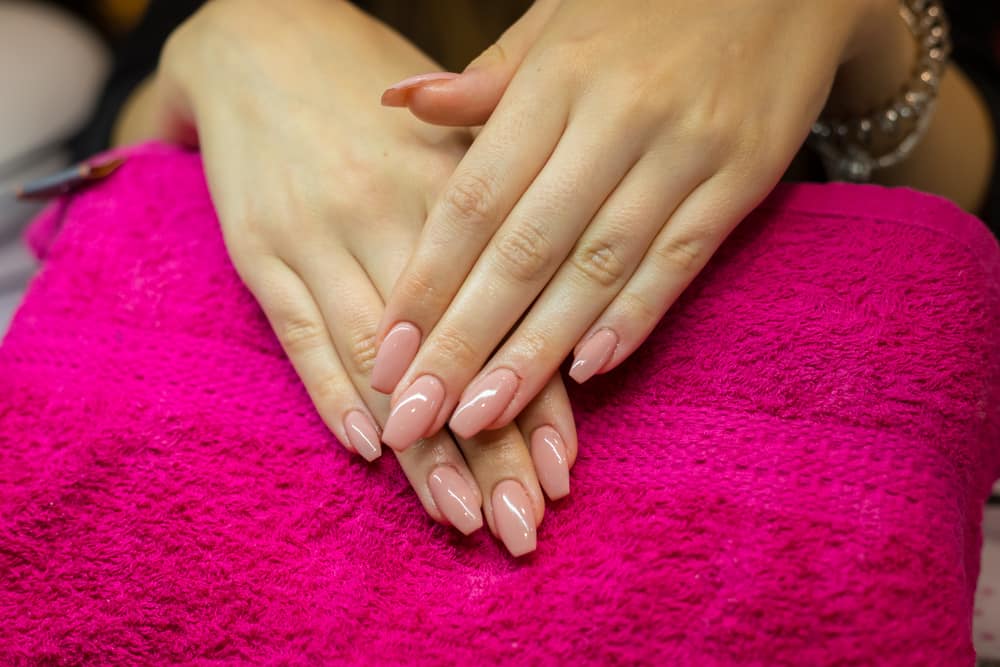 Women hands crossed on ping towel in nail salon