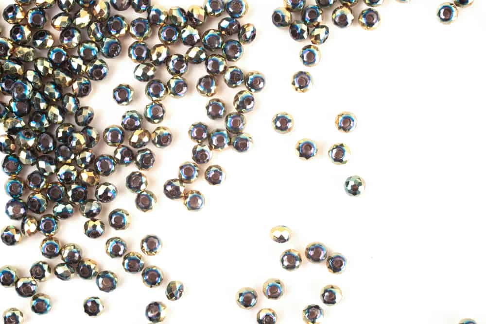 Green beads are scattered on a white background