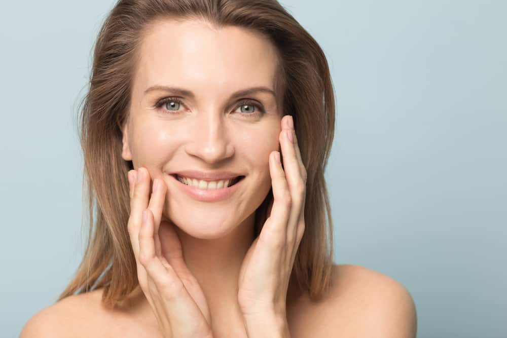 Head shot portrait smiling woman touching perfect smooth face skin