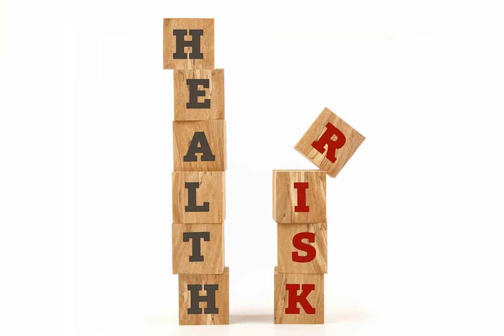 Health and Risk message written on cube shape wooden surface isolated on white background