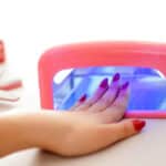 Woman drying her nail polish with uv lamp