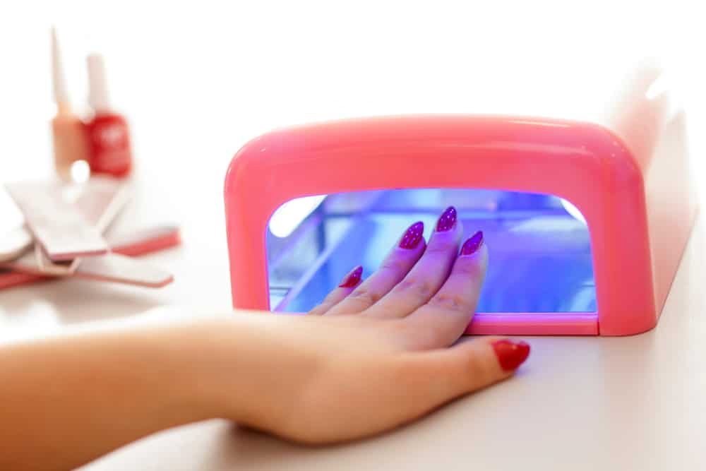 Woman drying her nail polish with uv lamp