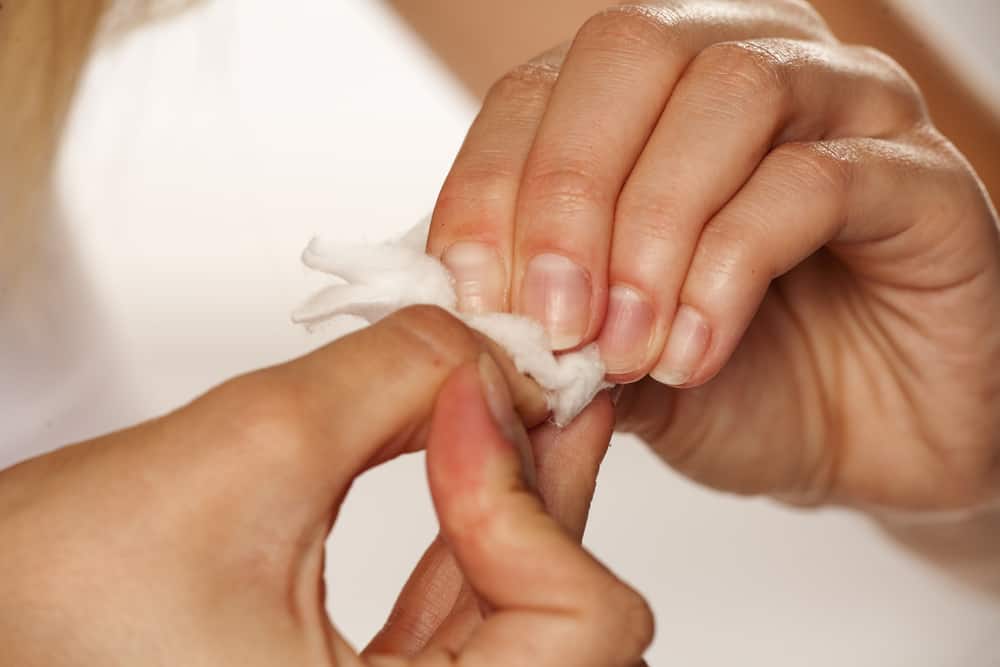 Woman removing a nail polish with cotton pad