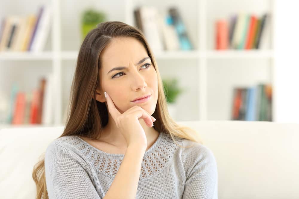 thinking woman wondering sitting on a sofa at home